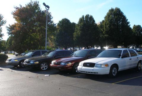 2001 Ford Crown Victoria - Several Ford Crown Victorias are parked in a lot on a sunny day.
