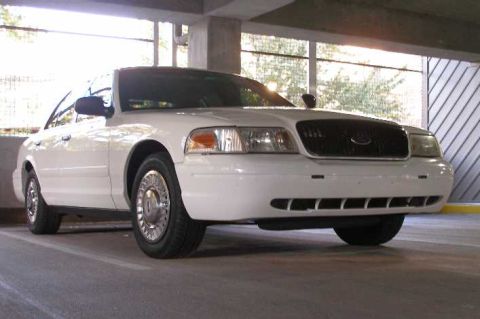 2001 Ford Crown Victoria - A white Ford Crown Victoria is parked in a covered lot, showing its front and side profile.