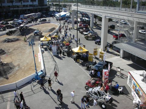 1998 Ford Crown Victoria - Elevated view of an outdoor event lot with a dirt course, yellow vendor tents, off-road buggies and crowds of attendees.
