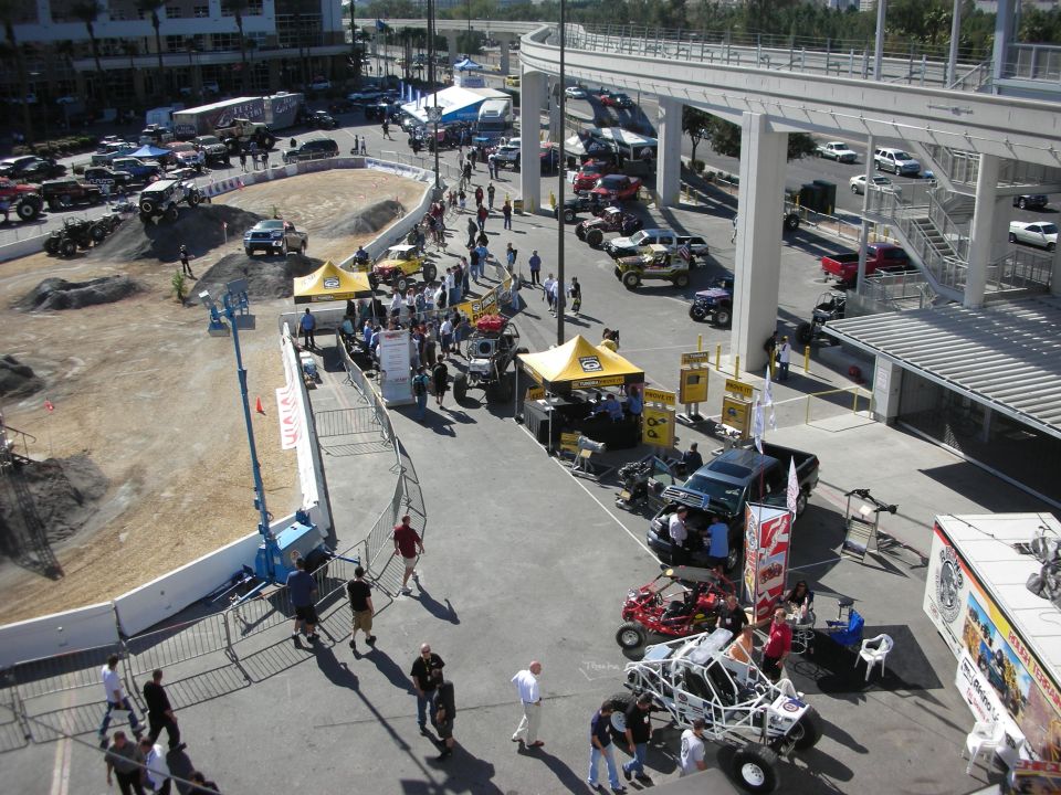 Elevated view of an outdoor off-road demo area with dirt track, tents and buggies