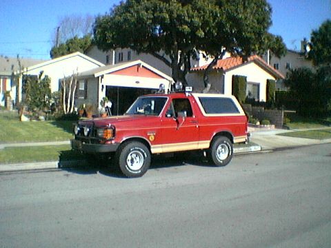 1989 Ford Bronco - This red 1989 Ford Bronco with tan trim is parked on a residential street.