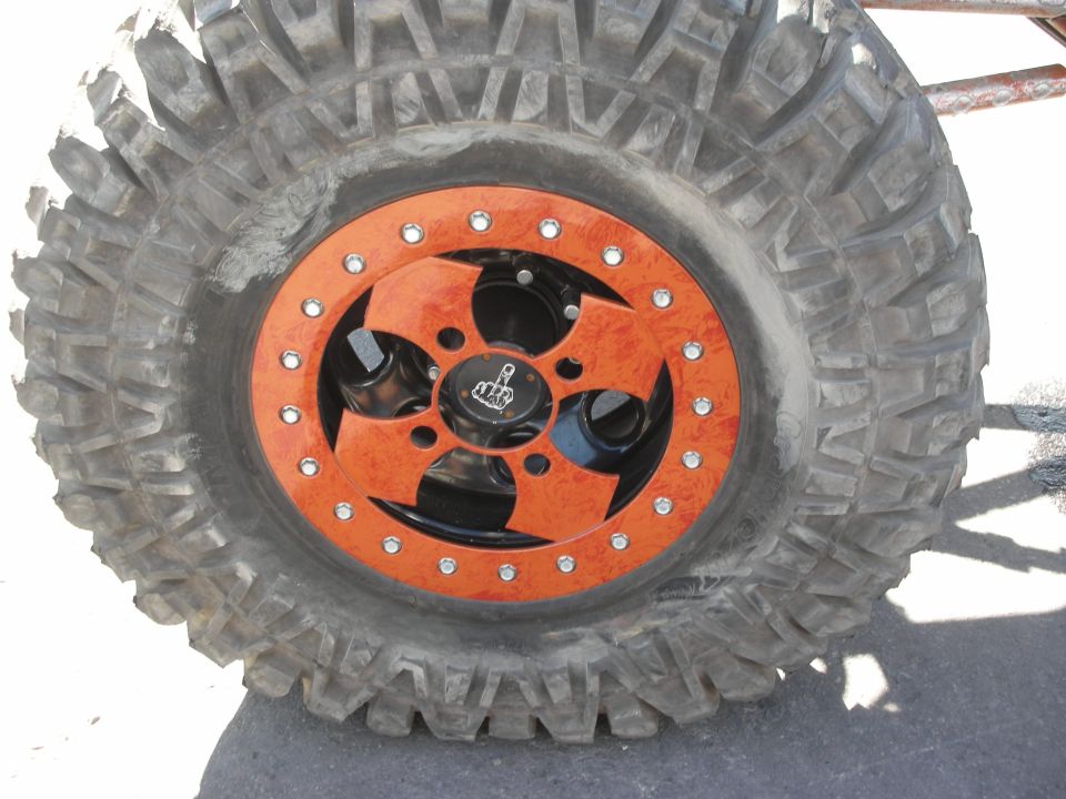 Close-up of a chunky off-road mud tire on a black-and-orange beadlock wheel