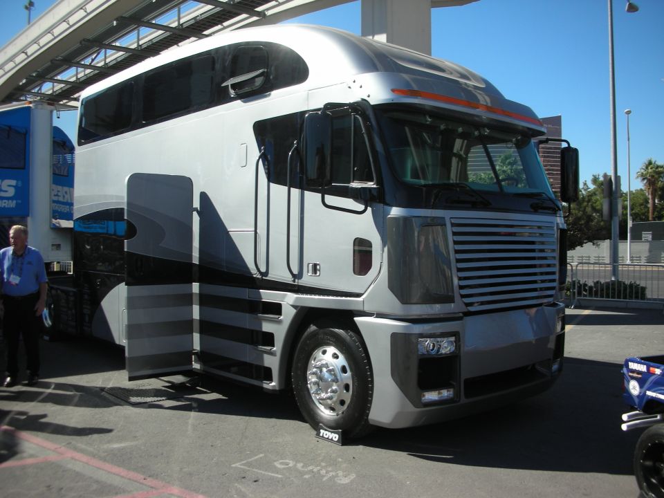 Silver cab-over conversion truck displayed outdoors at an event