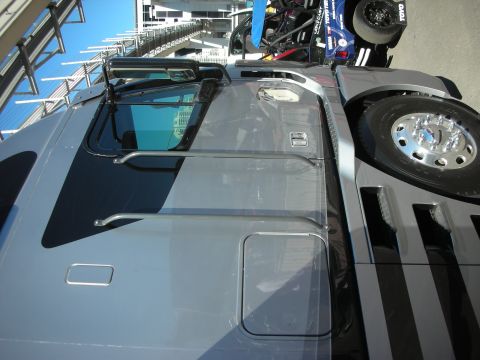 1998 Ford Crown Victoria - Looking down on the roof and windshield of a gray custom truck cab beside a chrome-rimmed spare wheel.