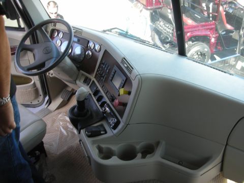 1998 Ford Crown Victoria - tan interior of a custom truck cab with steering wheel, gauges, floor shifter, and cup holders.