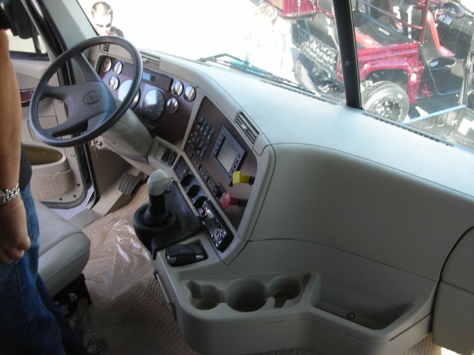 Interior of a custom truck cab showing tan dash, steering wheel, and shifter