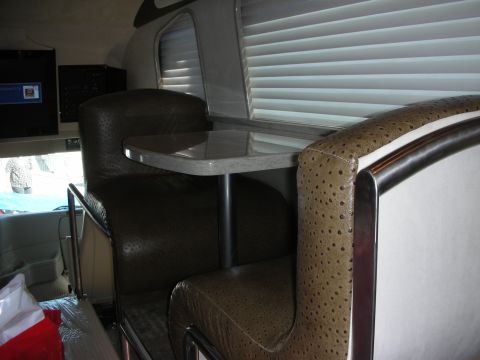 1998 Ford Crown Victoria - built-out coach interior featuring brown textured leather booth seats around a small table with window blinds behind.