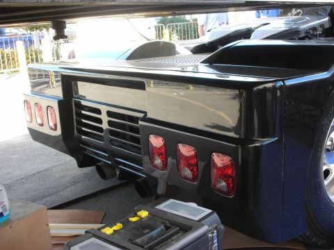 1998 Ford Crown Victoria - glossy black custom rear bumper with rows of round red tail lights, a vented center panel, and an exhaust opening.