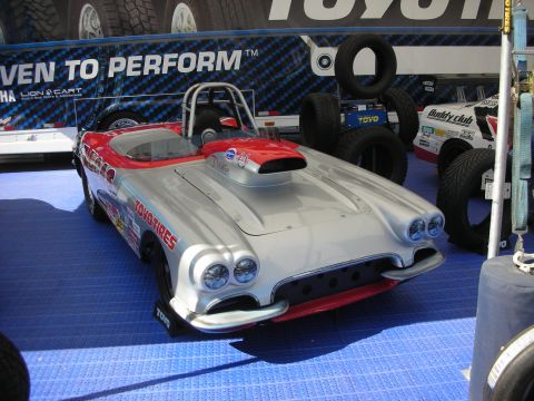 1998 Ford Crown Victoria - silver and red 1950s Corvette-style roadster set up as a drag car, with hood scoop and roll bar, in a Toyo Tires display.