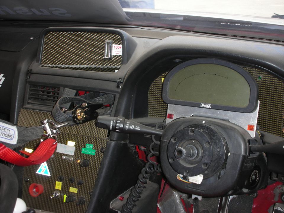 Race car cockpit with carbon-fiber dash, digital display, and harness belts