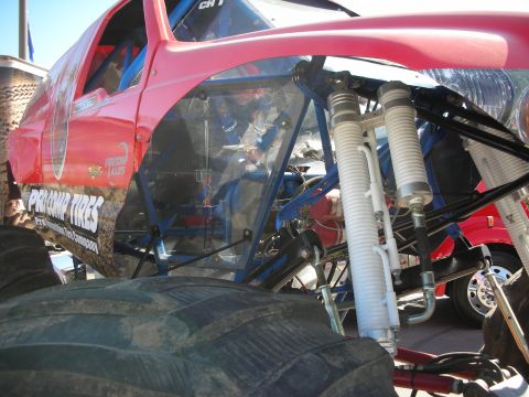 1998 Ford Crown Victoria - red-bodied tube-chassis off-road trophy truck with large coilover shocks and reservoir mounts, sponsored by Pro Comp Tires.