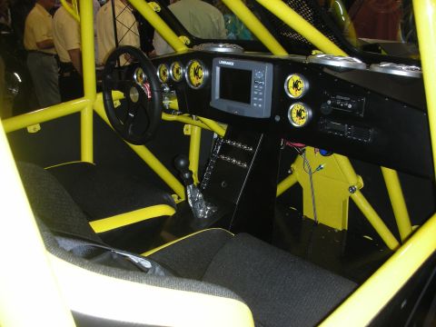 1998 Ford Crown Victoria - interior of a yellow tube-chassis off-road car showing roll cage, KC gauges, a Lowrance screen, and a fabric seat.