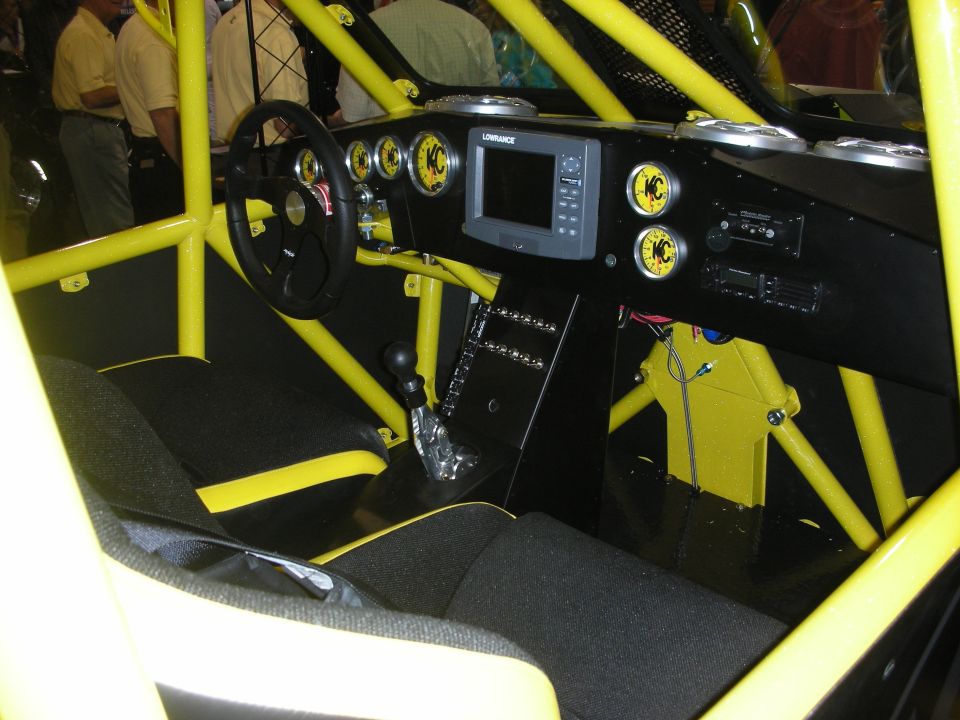 Yellow tube-chassis off-road car interior with roll cage, gauges, and screen