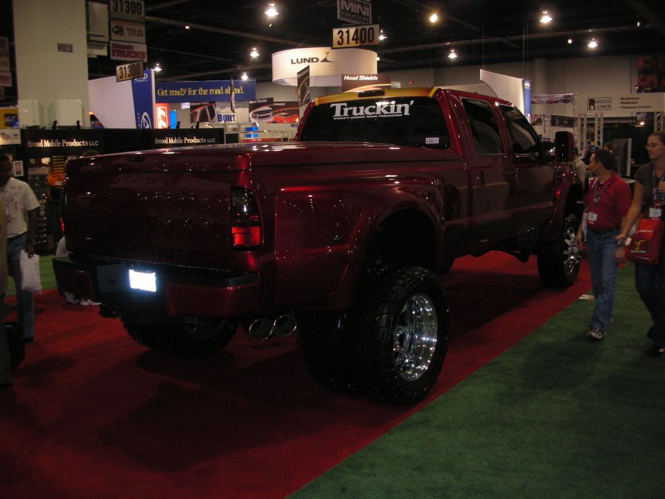 Rear view of a lifted dark red Ford dually pickup on a show floor