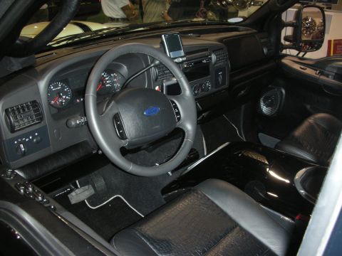 1998 Ford Crown Victoria - Black truck interior showing a Ford steering wheel, instrument cluster, automatic shifter and a dash-mounted GPS unit.