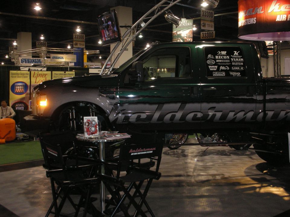 Dark green lifted truck with Geldermann graphics on display at an indoor expo