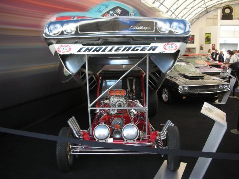 1998 Ford Crown Victoria - vintage-style front-engine dragster with its Challenger-bodied front end tilted up, exposing a blown chrome engine on a red chassis.