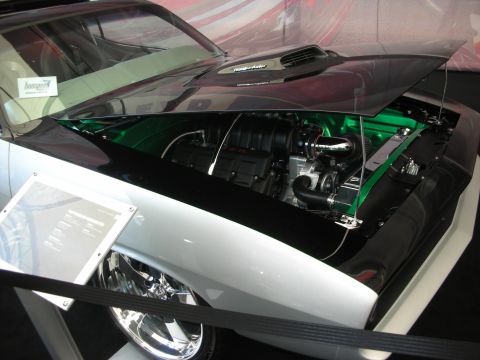 1998 Ford Crown Victoria - Open engine bay of a silver custom car showing a supercharged engine over a green-painted inner fender with chrome detailing.