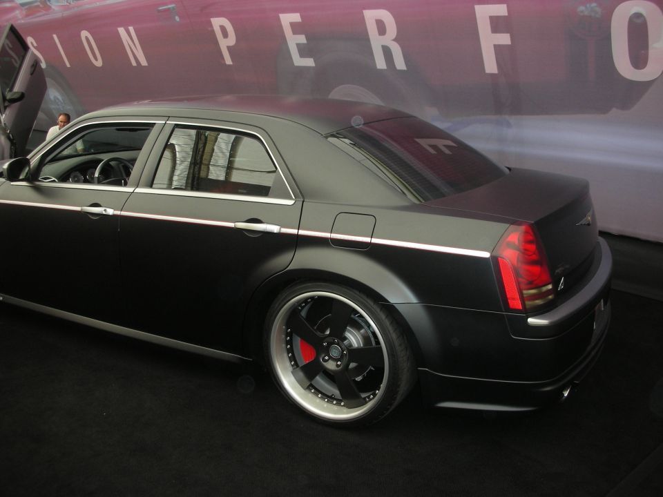 Rear three-quarter of a matte-black Chrysler 300 sedan on staggered wheels