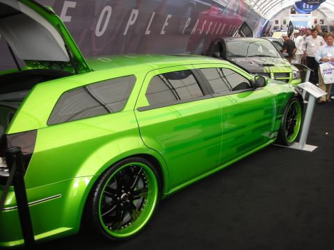 1998 Ford Crown Victoria - Glossy lime-green custom Dodge Magnum wagon, side view on black-and-green deep-dish wheels at an indoor auto show.