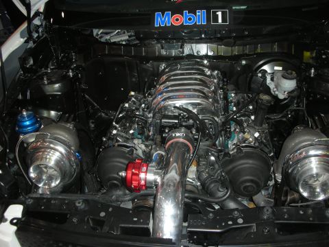 1998 Ford Crown Victoria - Twin-turbo V8 engine swap with polished intake, chrome piping and a red wastegate, beneath a Mobil 1 banner.