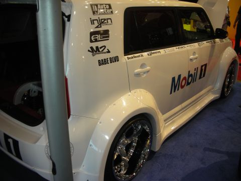 1998 Ford Crown Victoria - White widebody Scion xB show car on polished chrome wheels, side panel covered in sponsor decals including Mobil 1 and Injen.