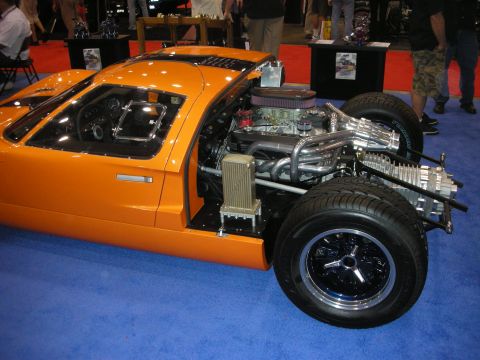 1998 Ford Crown Victoria - Orange mid-engine sports car displayed as a cutaway, exposing its V8 engine, transaxle and tubular chassis on blue carpet.