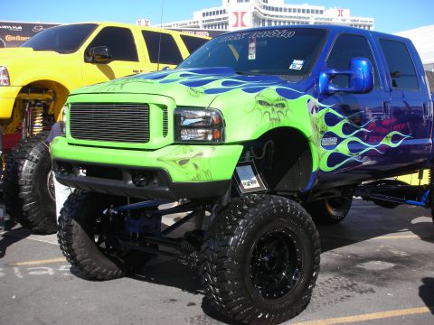 1998 Ford Crown Victoria - Heavily lifted pickup with a green skull-and-flames airbrushed front end transitioning to purple flames, on chrome wheels.