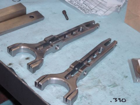 1979 Ford Bronco - Two metal clutch fork components are shown on a workbench, with the number .390 visible in the foreground.