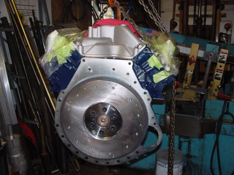 1979 Ford Bronco - Engine block and flywheel assembly suspended by chains in a workshop setting.