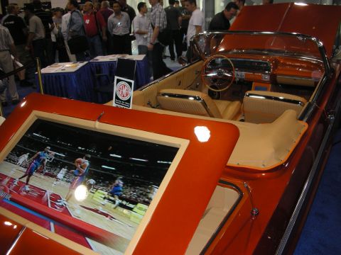 1998 Ford Crown Victoria - orange classic convertible with cream upholstery shows a built-in flat-screen displaying a basketball game.