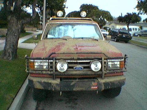 1989 Ford Bronco - This 1989 Ford Bronco is covered in mud, showing its front grille and lights.