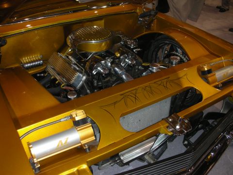 1998 Ford Crown Victoria - Detail of a gold custom car's engine bay with a chrome air cleaner, polished components and pinstriped trim.