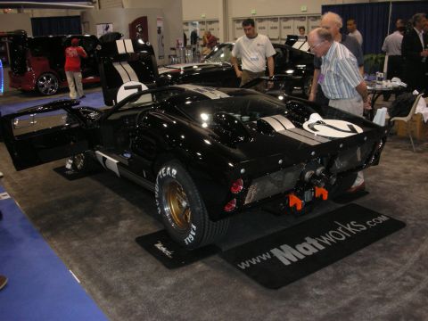 1998 Ford Crown Victoria - black GT40-style race car with white stripes and number 2 sits on a Matworks mat as a visitor inspects it.