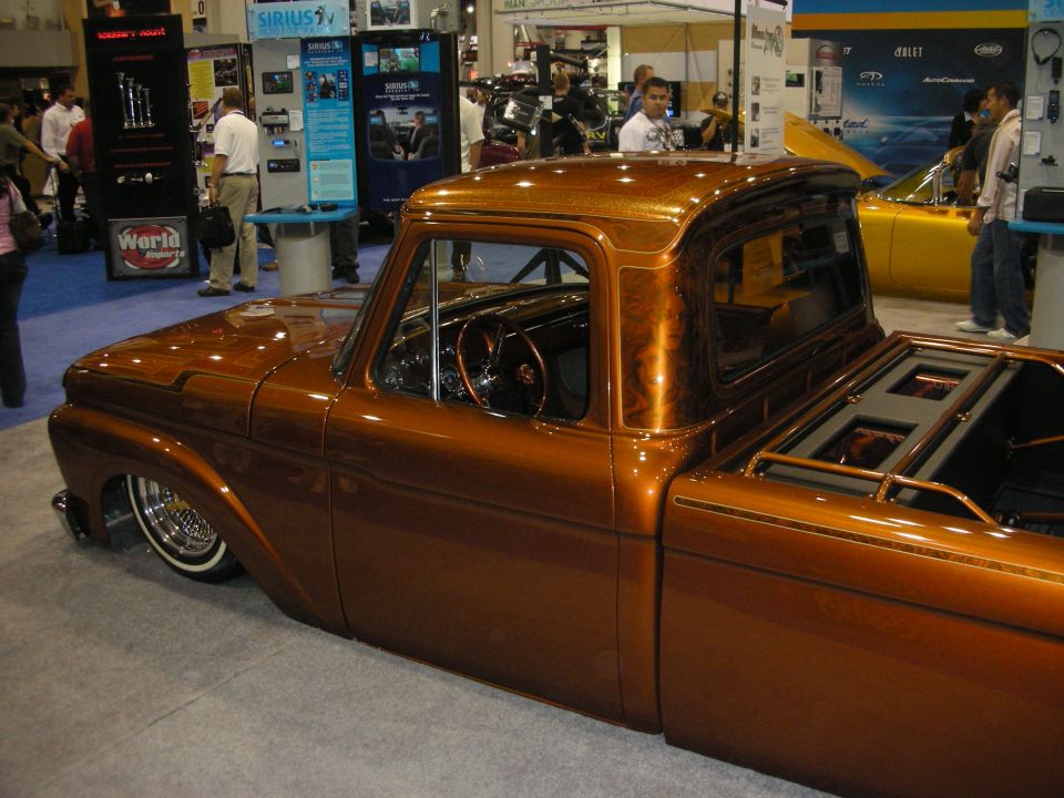 Lowered copper-orange custom pickup truck on wire wheels at an indoor show