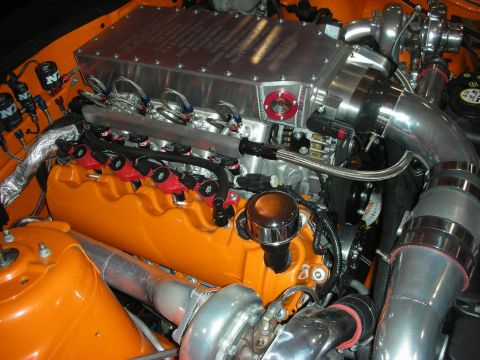 1998 Ford Crown Victoria - close-up of a twin-turbo orange V8 shows polished intake piping, red plug wires and braided fuel lines.