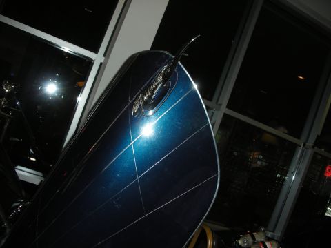 1998 Ford Crown Victoria - sloped blue metalflake hood with a chrome script emblem is photographed at night near windows.