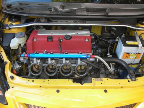 1998 Ford Crown Victoria - yellow car's engine bay shows a red-topped four-cylinder with individual throttle bodies, blue fuel rail and strut bar.