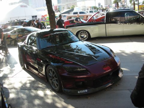 1998 Ford Crown Victoria - dark candy-red Honda S2000 roadster with an aggressive body kit sits on display at an outdoor car show.