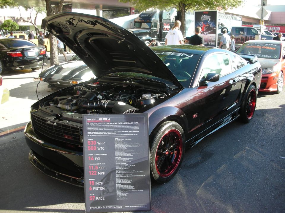 Black Saleen supercharged Mustang with red wheels and info placard