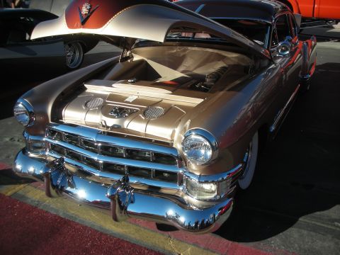 1998 Ford Crown Victoria - gold custom 1949-era Cadillac lead sled sits with hood open, showing whitewall tires and heavy chrome bumper and grille.