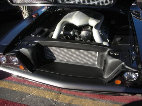 1998 Ford Crown Victoria - black exotic-style car with hood open showing a silver intake and a large front-mounted intercooler over red and yellow curbing.