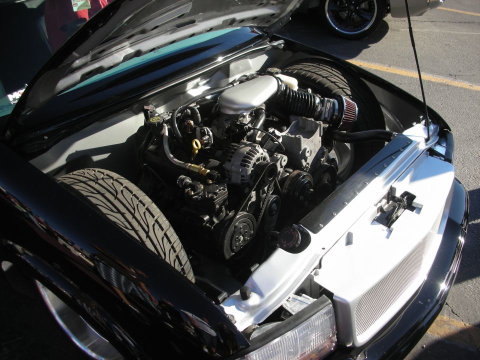 V8 engine bay with cone air filter in a black car at car show
