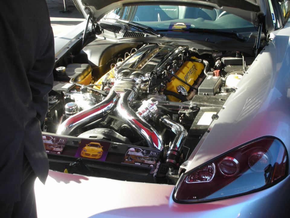Silver car engine bay with chrome headers and yellow valve covers
