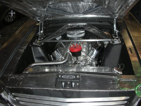 1998 Ford Crown Victoria - unpainted bare-metal car engine bay holding a V8 with a red distributor, chrome air cleaner and a tubular strut brace.