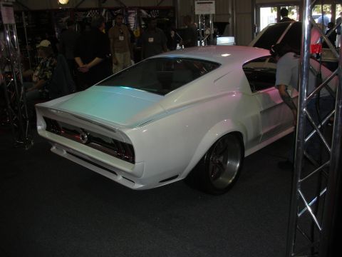 1998 Ford Crown Victoria - white pearl color-shifting custom 1967-68 style Mustang fastback shown rear three-quarter on staggered wheels at an indoor display.