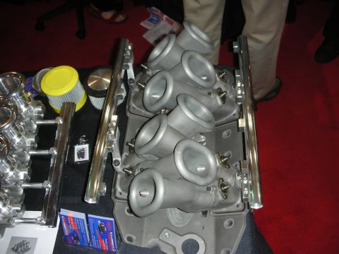 1998 Ford Crown Victoria - Cast aluminum cross-ram intake manifold fitted with fuel rails and filter, shown on a red-carpeted display table.