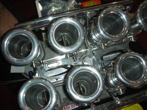 1998 Ford Crown Victoria - Overhead view of a row of large polished individual throttle bodies mounted on a V8 intake manifold.
