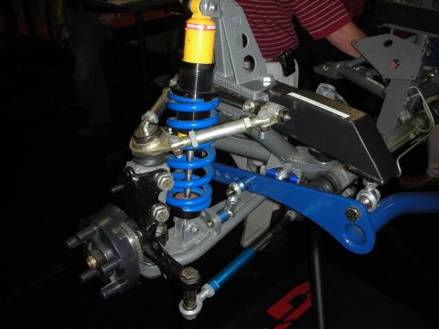 1998 Ford Crown Victoria - Custom front suspension upright with blue coilover spring, yellow shock, and blue tubular control arm on display.