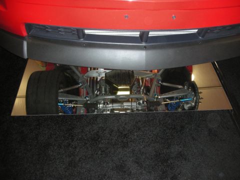 1998 Ford Crown Victoria - Front underside of a red car displayed over a mirror panel, revealing the suspension, steering, and drivetrain.